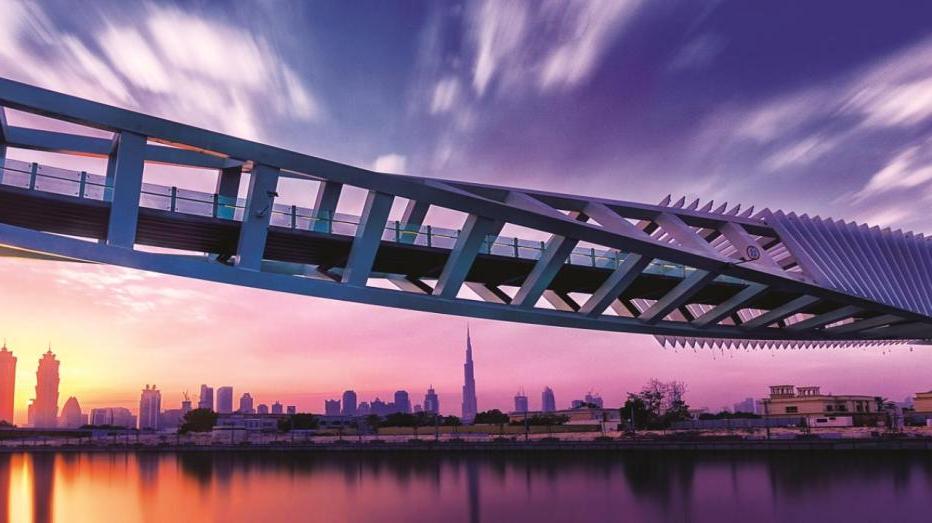 迪拜水渠近距离-粉红色和紫色的色调与城市景观和桥梁